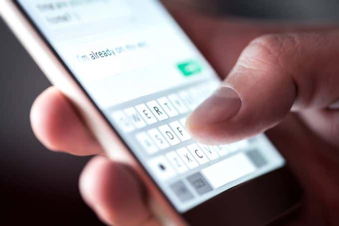 Man sending text message and sms with smartphone. Guy texting and using mobile phone late at night in dark. Communication or sexting concept. Finger typing with cellphone keyboard. Light from screen. - Online Tech Tips Can’t Send Text Messages From Android? 4 Fixes to Try image
